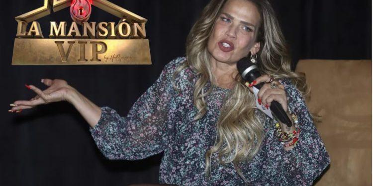 Female Presenter on a Dark Stage, Speaking into a Handheld Microphone, Wearing a Floral Dress with Bracelets; 'la Mansión Vip' Logo Appears in the Upper Left. › Guadalupa Ciudadana