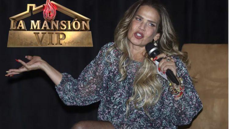Female Presenter on a Dark Stage, Speaking into a Handheld Microphone, Wearing a Floral Dress with Bracelets; 'la Mansión Vip' Logo Appears in the Upper Left. › Guadalupa Ciudadana