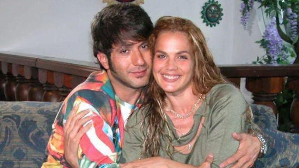 a Couple Sits Closely on a Patterned Sofa; the Man Wears a Colorful Shirt and the Woman Has Long Blonde Hair, Smiling in a Decor-filled Room. › Guadalupa Ciudadana