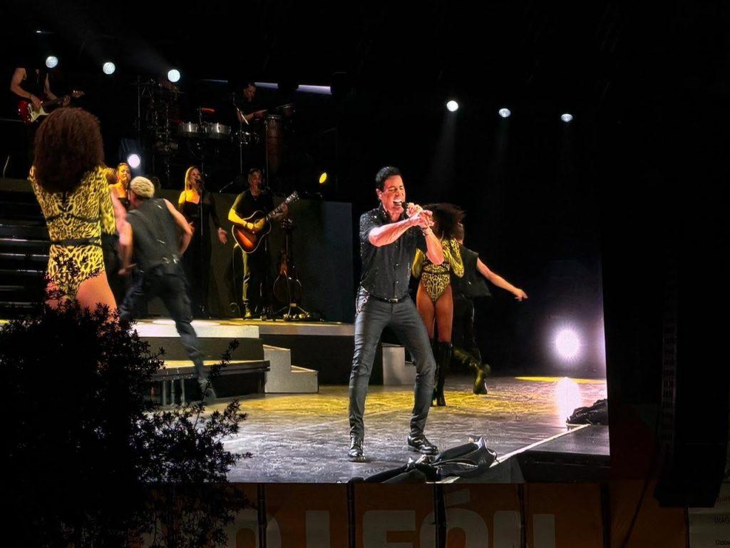 Male Singer in Black Shirt Performs Center Stage with Band and Dancers on a Lit Concert Set After-dark Onstage Lighting in the Background. › Guadalupa Ciudadana