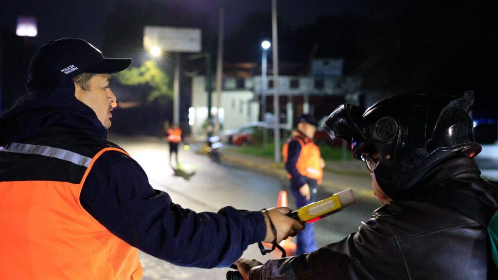 Nighttime Police Checkpoint: an Officer in an Orange Vest Administers a Breathalyzer to a Motorcyclist, with Cones and Other Officers in the Background. › Guadalupa Ciudadana